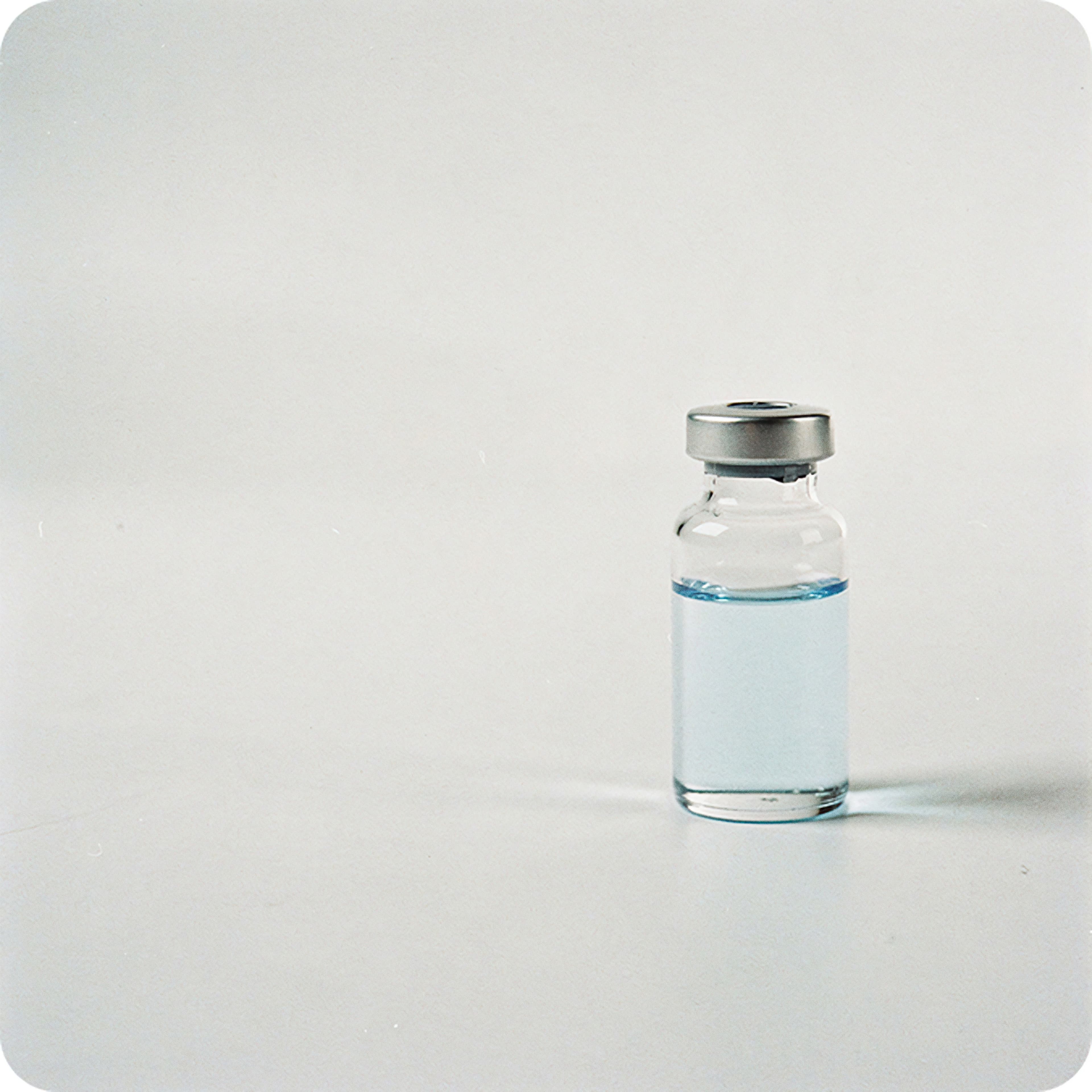 Glass medicine vial on a white surface, representing healthcare